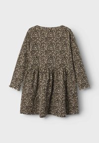 Langemouwen jurk in beige met een zwart gespikkeld patroon, met een uitlopende rok en een ronde halslijn, gemaakt van zacht stof.