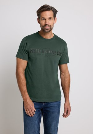 Waldgrünes Baumwoll-T-Shirt mit Rundhalsausschnitt, das auf der Vorderseite den Druck "FIELD & STONE CO." in dunkler Schrift zeigt.