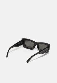 Lunettes de soleil noires de forme rectangulaire, avec une monture en plastique lisse et des verres foncés. Présentent des branches droites pour un look moderne.