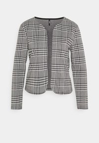 Chaqueta con patrón de pata de gallo en blanco y negro, manga larga, cuello redondo y diseño con frente abierto. Confeccionada con una tela texturizada.