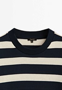 Pull en maille à rayures horizontales bleu marine et blanc avec col ras du cou côtelé et étiquette de marque à l'intérieur du col.