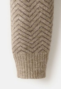 Manica di maglione beige lavorata a maglia con motivo a spina di pesce marrone scuro e polsino a coste. Texture morbida, spessore medio.