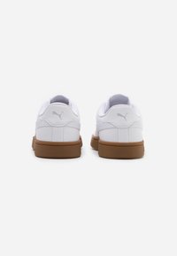Sneakers bianchi con tomaia in pelle liscia, dettagli in rete e suola in gomma marrone. Presentano un logo discreto sul tallone.