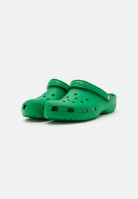 Zoccoli in gomma verdi con fori di ventilazione, tacco rialzato e soletta texturizzata. Logo Crocs sulla fascia, leggeri e facili da pulire.