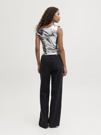 Top senza maniche di un blu metallizzato con un taglio leggermente sceso sulle spalle, abbinato a jeans neri a vita alta e larghi. Texture e vestibilità lisce.