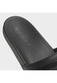 Black Adidas slide sandal featuring a textured footbed with embossed logo, smooth straps, and a sleek design.