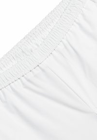Pantalones cortos con cinturilla elástica blanca, de textura suave y diseño limpio, con tejido fruncido en la cintura y las costuras laterales.
