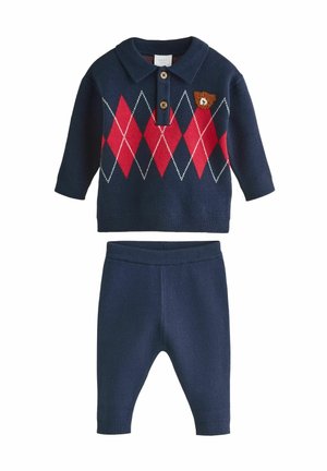 Navyblauer Strick-Zweiteiler mit einem kragenlosen Oberteil in Rot und Rautenmuster, Knopfverschluss und passender Hose mit geripptem Bund.