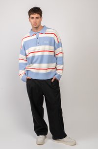Light blue striped sweater with red and white horizontal stripes, buttons on collar, textured fabric, paired with black pants and white sneakers.