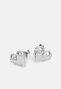 Orecchini a forma di cuore in argento con una finitura lucida e una delicata incisione "Calvin Klein." Presentano una chiusura a clip per una vestibilità sicura.