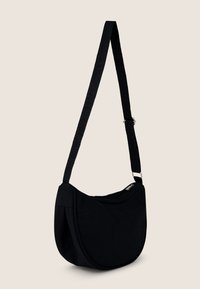 Borsa a spalla nera in tela con forma curvata, tracolla regolabile e chiusura con zip. Presenta una texture liscia e un design minimale.