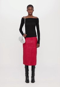 Črna off-the-shoulder dolga majica, rdeča usnjena midi krilo, črne visoke škornje in srebrna torbica. Gladke teksture in bold barve.