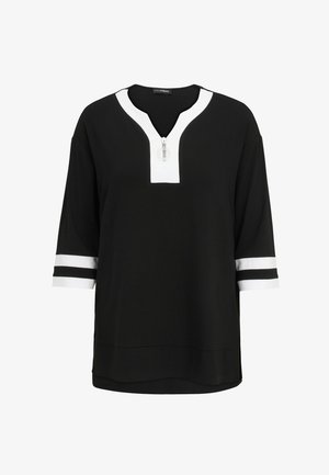 Schwarzes Trikotoberteil mit weißem V-Ausschnitt und Reißverschluss, drei Viertel langen Ärmeln mit schwarz-weißen Streifen. Weiche Textur, lockere Passform.