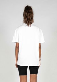 Hvid bomulds T-shirt med korte ærmer, afslappet pasform og rund udskæring, set fra ryggen. Ingen synlige mønstre eller hardware.