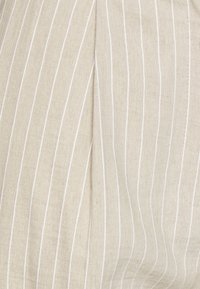 Linneduk i ljusbeige med smala vita ränder. Mjuk textur med synlig väv och små variationer som ger ett naturligt utseende.