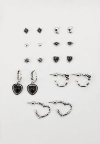 Ensemble de boucles d'oreilles en argent et noir, comprenant des designs de cœur, d'étoile et de lune. Différentes formes : clous, créoles et pendantes.