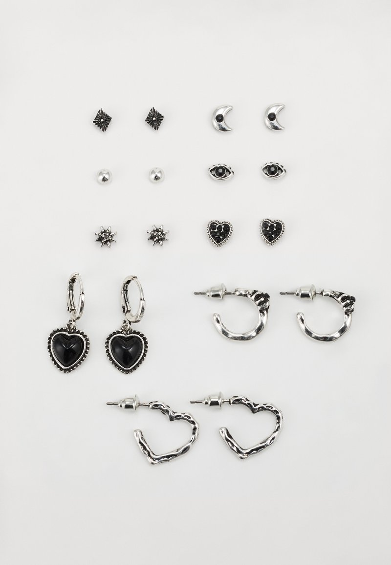 Ensemble de boucles d'oreilles en argent et noir, comprenant des designs de cœur, d'étoile et de lune. Différentes formes : clous, créoles et pendantes.