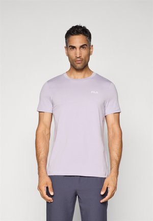 T-shirt violet clair avec un col rond et des manches courtes. Présente un petit logo FILA blanc sur la poitrine. Texture douce et lisse.