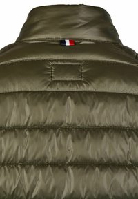 Olivgrüne Pufferjacke mit hohem Kragen, die über gesteppte Bereiche verfügt und ein kleines tricolores Stoffdetail in der Nähe des Halses hat.