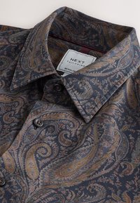 Pikalõhikaline särk tumedas kangas, millel on paisley-muster mereväe, kuldsete ja roostevärviliste toonidega. Komplektis on krae ja nööbikinnitused.