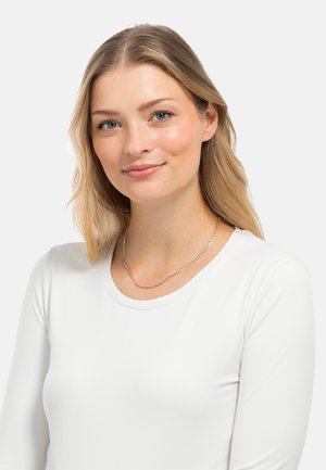 Top bianco a maniche lunghe con scollatura rotonda abbinato a una collana in oro, caratterizzato da una texture liscia e un sottile design curvilineo.