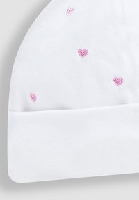 Beanie bianco in cotone con risvolto, caratterizzato da cuori rosa ricamati sparsi su tutta la superficie. Texture morbida, design casual.