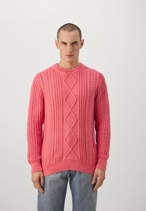 Strikket pullover i lys pink med et tekstureret kabelmønster og ribstrikkede manchetter. Crew neck-design og løs pasform, parret med lyse denim.