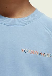 Felpa azzurro chiaro in cotone misto, con collo girocollo a coste e logo ricamato "SCOTCH & SODA" in colori vivaci.