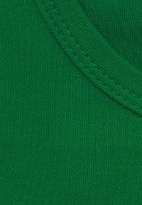 Green cotton fabric with a smooth texture and a V-neck design. Features subtle stitching along the neckline, creating a clean finish.