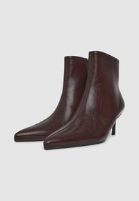 Stivali alla caviglia in pelle borgogna con punta affilata, design elegante e tacco piccolo; la superficie presenta una finitura testurizzata sottile.