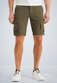 Shorts cargo vert olive avec plusieurs poches latérales, une taille élastique et des détails de couture. Associés à des baskets blanches.