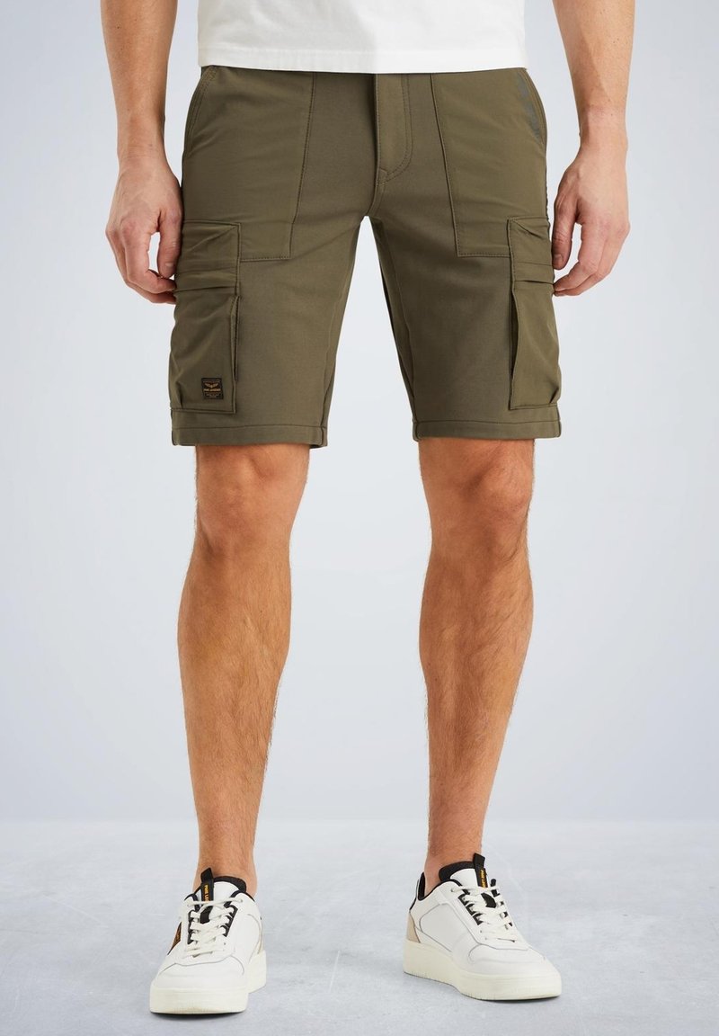 Shorts cargo vert olive avec plusieurs poches latérales, une taille élastique et des détails de couture. Associés à des baskets blanches.