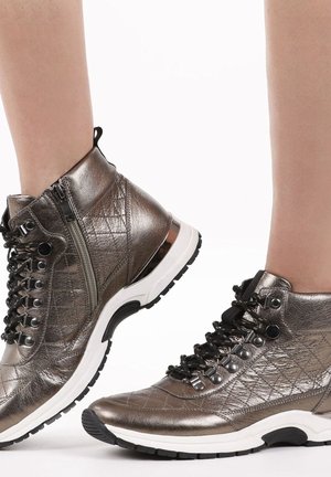 Bottes chelsea en bronze métallique avec texture matelassée, lacets noirs, accents en métal argenté et semelles en caoutchouc blanc offrant une adhérence texturée.