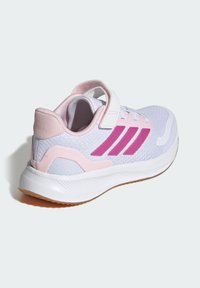 Zapato deportivo ligero con parte superior de malla en blanco y detalles en rosa, con tres franjas rosas, una correa de velcro y suela texturizada.