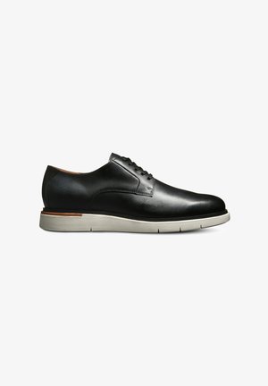 Black leather dress shoe with a rounded toe, minimal lacing, and a contrasting gray sole. Subtle stitching details and smooth texture.