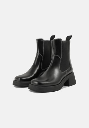 Schwarze Leder Chelsea-Stiefel mit einem klobigen Absatz, elastischen seitlichen Einsätzen und kontrastierendem weißen Nähten. Strukturierte Oberfläche.