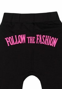 Schwarze Leggings mit dem Aufdruck "FOLLOW THE FASHION" in leuchtendem Pink auf der Rückseite, mit weichem Stoff und enganliegender Passform an der Taille.