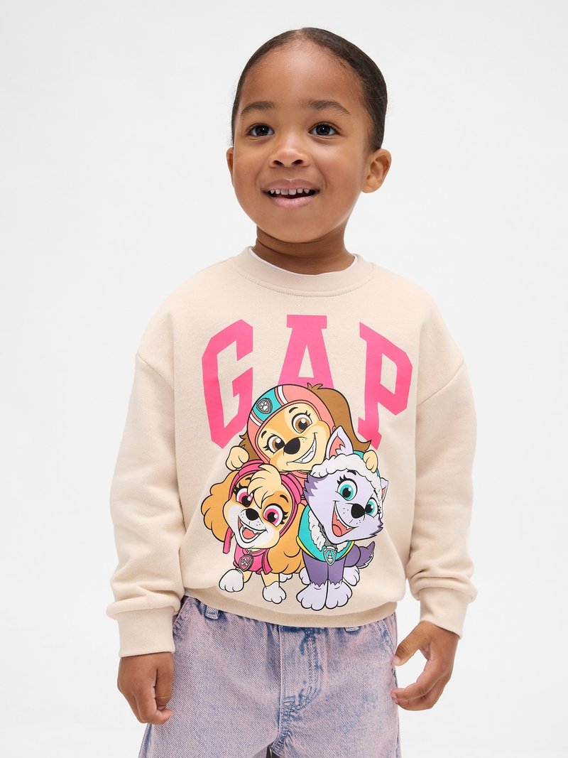 Beige sweatshirt featuring large pink "GAP" logo and cartoon dogs in vibrant colors. Soft texture, relaxed fit, ideal for casual wear.