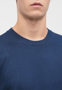 Camiseta de algodón color Navy con un clásico cuello redondo. Textura suave con mangas cortas, adecuada para un estilo casual.