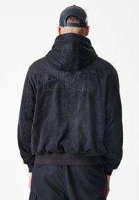 Crna hoodie napravljena od mekanog materijala sličnog nubuku, s velikim reljefnim logotipom "LAKERS" na leđima. Riblje manžete i donji rub upotpunjuju dizajn.