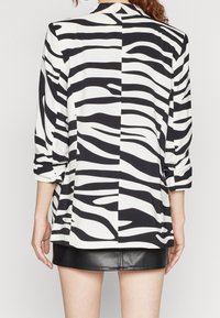 Černobílé sako se zebra pruhy, tříčtvrtečními rukávy, lehkým materiálem a mírně oversized střihem. Kombinováno s černou koženou sukní.