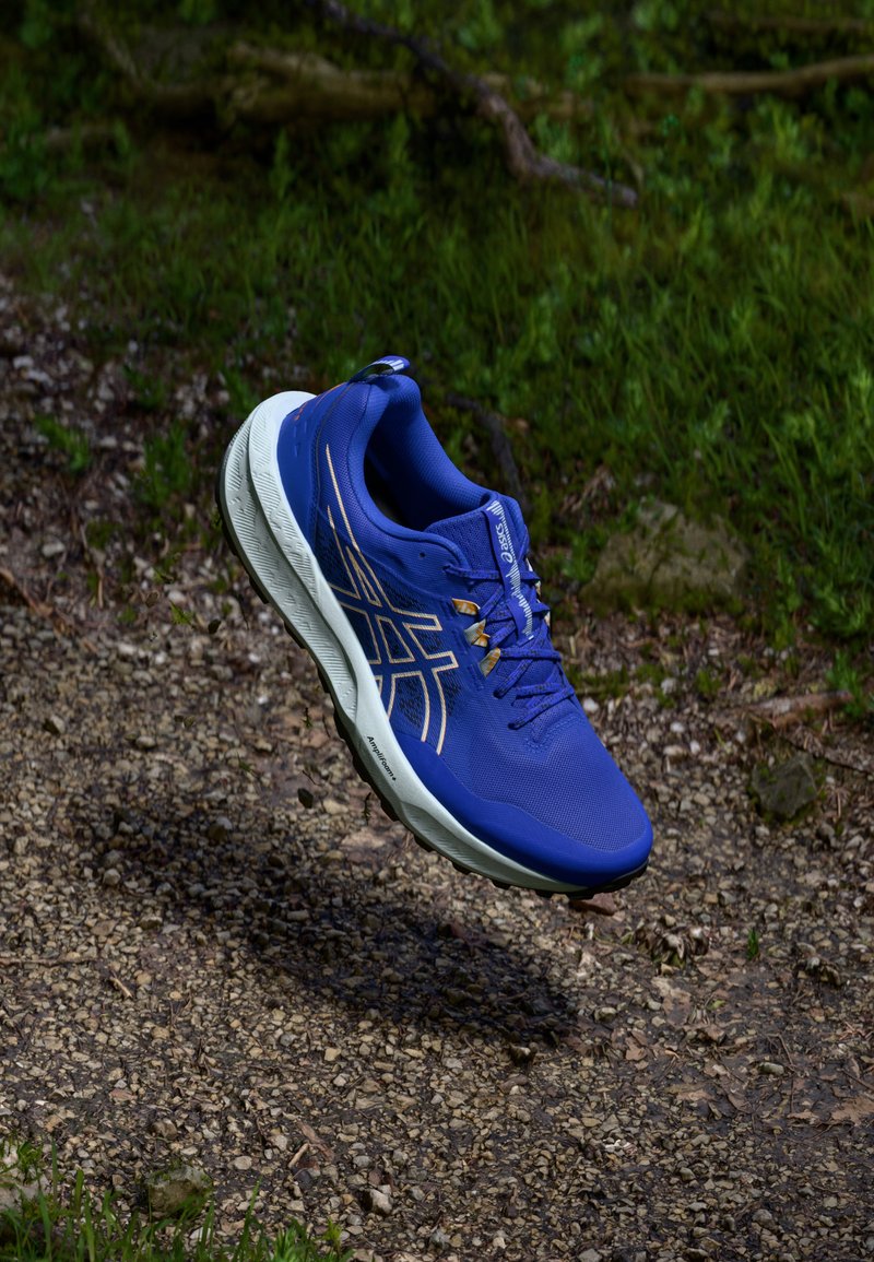 Blue athletic shoe with a mesh upper, white sole, and gold accents, featuring a lace-up design and visible cushioning for comfort.
