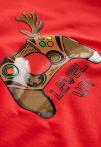 Red fabric featuring a graphic of a brown game controller with antlers, a red button, and the text "LEVEL UP!" in black.