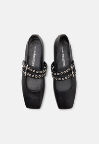 Chaussures en cuir noir à enfiler avec des pointes carrées, ornées de doubles sangles décorées de rivets en argent et d'une texture lisse.