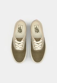 Adidași din pânză de culoare verde măslin și bej, cu șireturi albe, vârf rotund, cusături contrastante și un logo pe branț.