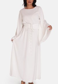 Witte maxi-jurk met lange mouwen, een getailleerde taille, veterdetail en vloeiende stof. Voorzien van brede mouwen en een subtiele glans.