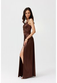 Hnědá saténová maxi šaty s přiléhavým tělem, detailem do kříže a vysokým bočním rozparkem. Obsahuje tenké ramínka a splývavou sukni.