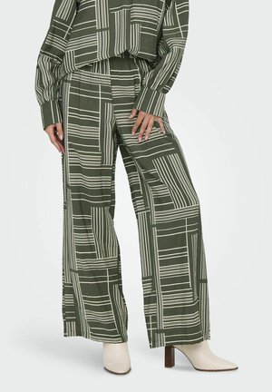 Groene, gepatternde wijde broek met witte geometrische lijnen, gemaakt van zachte stof, gecombineerd met crèmekleurige enkellaarsjes met een blokhak.