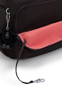 Black fabric bag with a coral zip pocket, featuring a furry black gorilla keychain and a silver metal clasp detail.