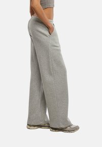 Pantaloni da jogger grigi a gamba larga realizzati in tessuto morbido, dotati di tasche laterali e di una vita elastica per il massimo comfort. Vestibilità casual e rilassata con texture semplice.